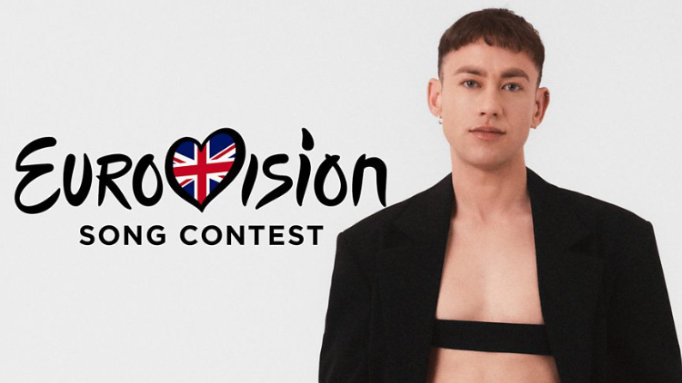 Olly Alexander looks into camera next to the Eurovision logo