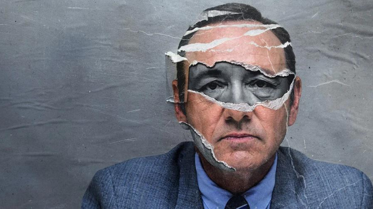 A graphic of Kevin Spacey's face pasted onto a wall, torn in the section with his eyes on it to reveal the same photo, but in black and white