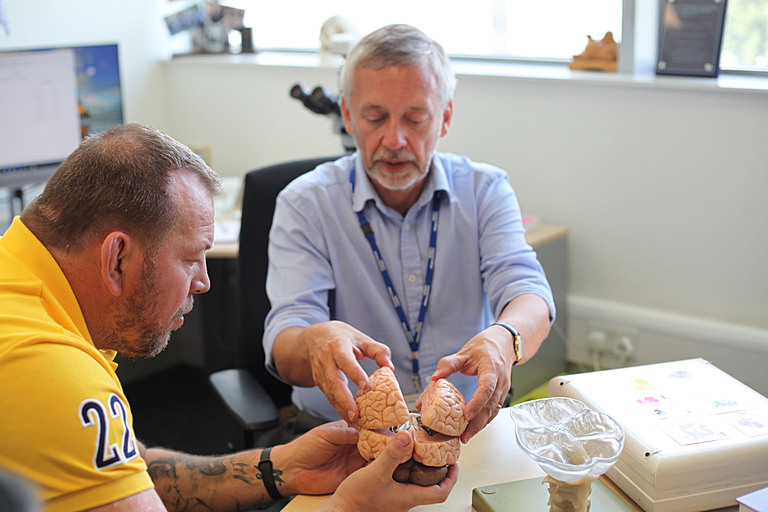 Steve Thompson MBE is holding a human brain model, at the Imperial College London brain bank