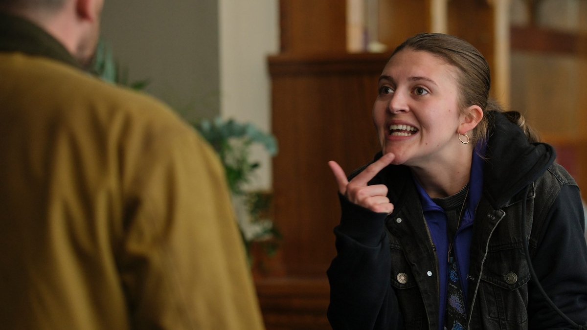 Lara places her index finger emphatically on her chin, likely in the midst of speaking BSL 