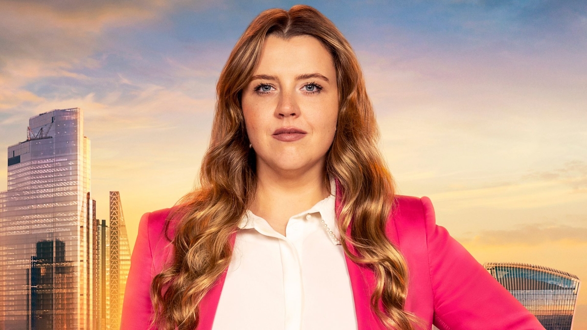 Emma Rothwell looks into the camera in front of the London skyline, wearing a pink blazer and a white shirt