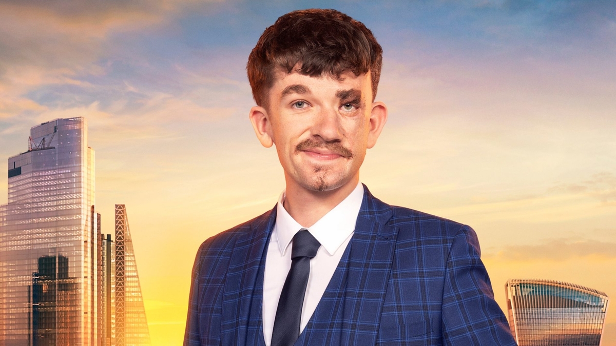 Jonny Heaver looks into the camera in front of the London skyline, wearing a check blue blazer and waistcoat, white shirt and deep blue tie