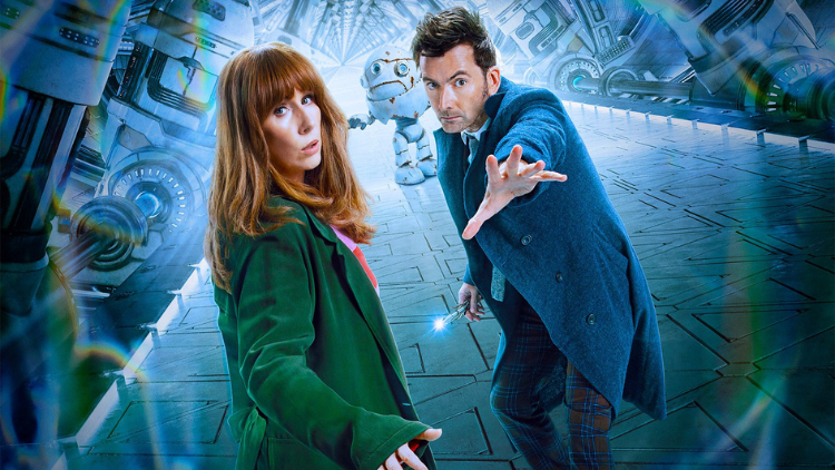 The Doctor, as played by David Tennant, looks into the camera with his hand out to the viewer, stood next to Donna Noble, also looking into the camera. A white, rotund robot is stood in the background, further down a corridor lined by industrial-looking white machinery