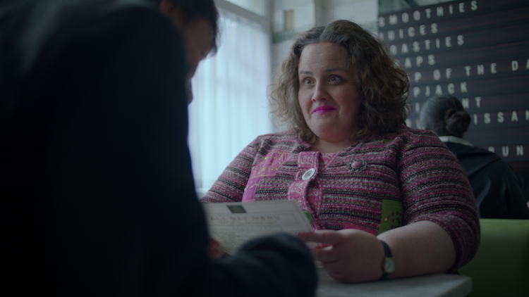 Jessica Gunning, a woman in her thirties, sits indoors looking at someone whose face we don't see