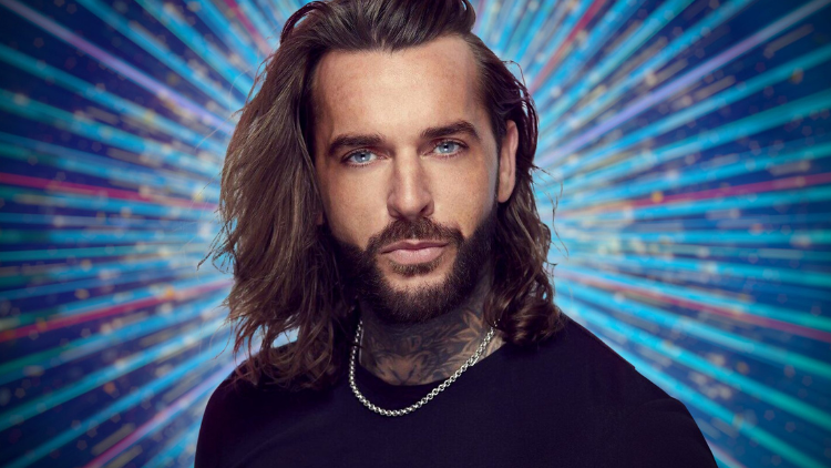 A photo of Pete Wicks in front of a glittery blue backdrop