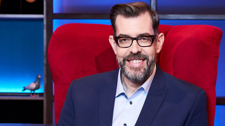 Richard Osman smiles into the camera