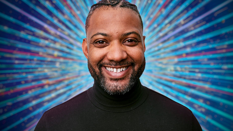 A photo of JB Gill in front of a glittery blue backdrop