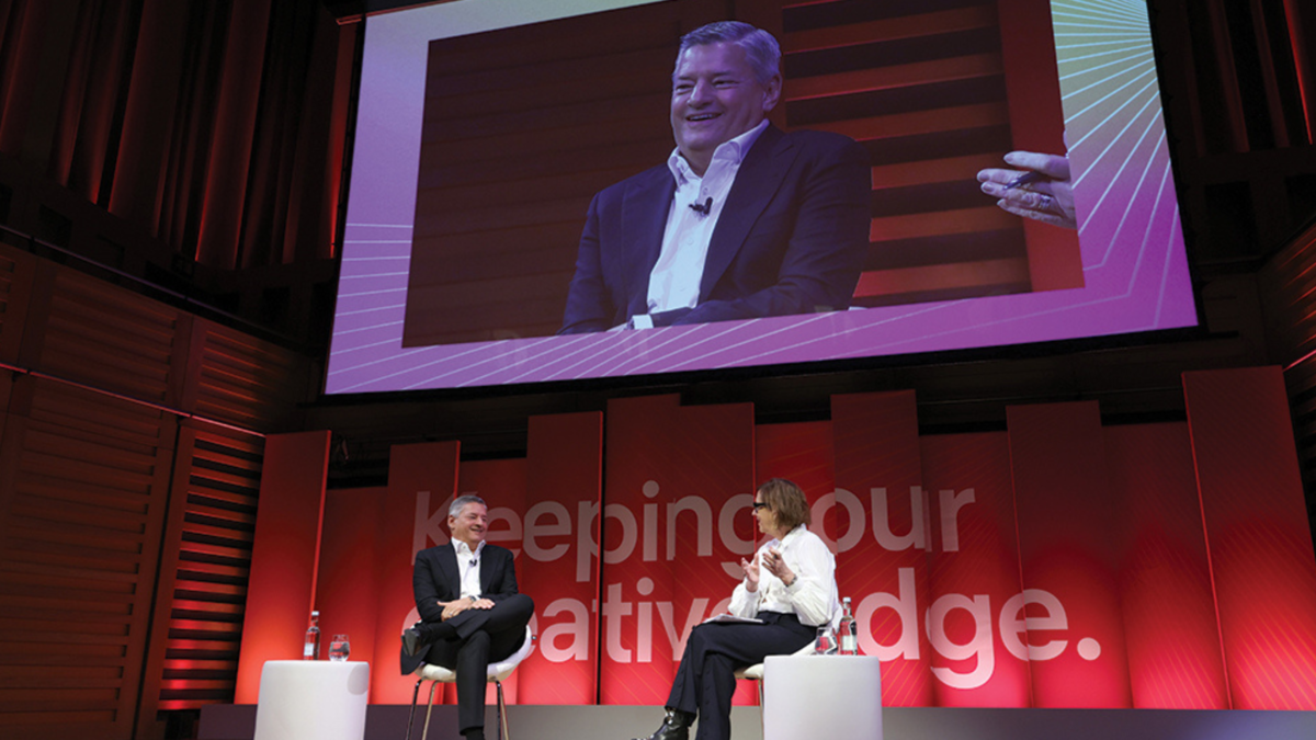 Ted Sarandos talks with Kirsty Wark onstage at the RTS London Convention, beneath a screen showing a live feed of Sarandos