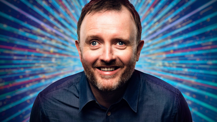 A photo of Chris McCausland in front of a glittery blue backdrop