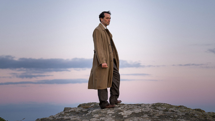 Matthew Rhys stands on a cliff, looking desolate