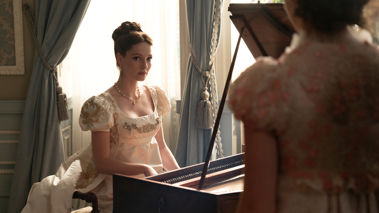Hannah Dodd as Francesca Bridgerton playing piano, looking at someone stood with their back to camera