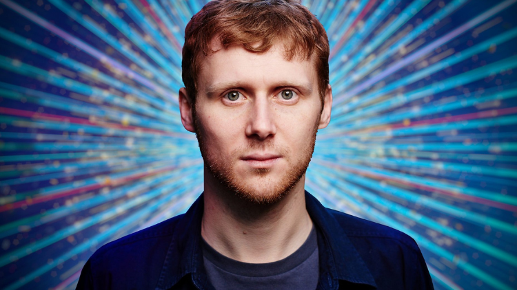 Jamie Borthwick looks into the camera in front of a glittery blue backdrop