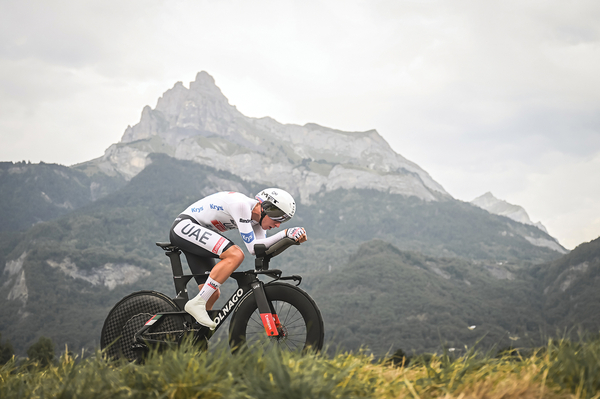 A professional cyclist rides the Tour de France for Team UAE against a mountainous backdrop