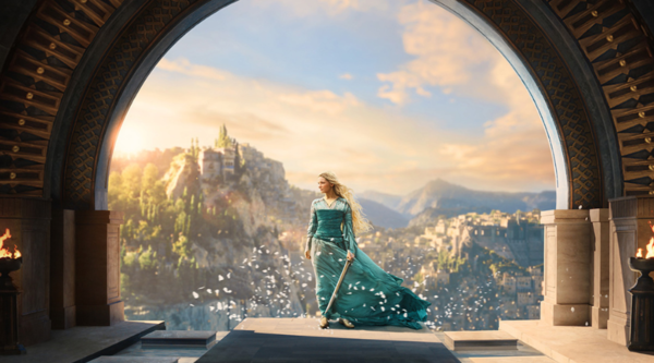 A young Elven woman with long blond hair in a green dress carrying a sword, stands in front of a grass covered mountain