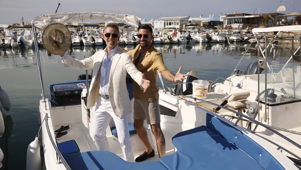 Anton du Beke and Giovanni Pernice stand on a boat in a harbour 