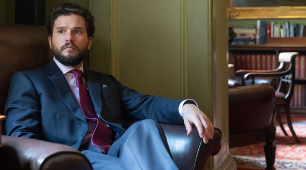 Kit Harrington sits indoors, wearing a suit, and looking off-camera