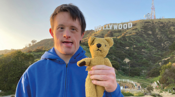 Tommy Jessop holds a stuffed bear, standing by the Hollywood sign in Los Angeles