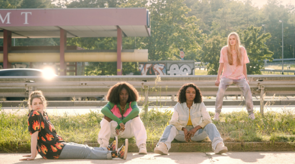 Four young women, the cast of Then You Run, are in a line in the middle of a motorway
