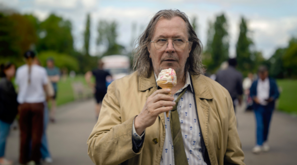 Gary Oldman as Jackson Lamb holds a 99 ice cream with strawberry sauce and a flake as he walks down a British street