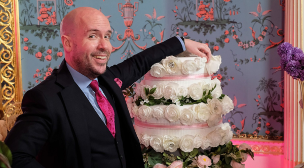 Tom Allen poses by a wedding cake