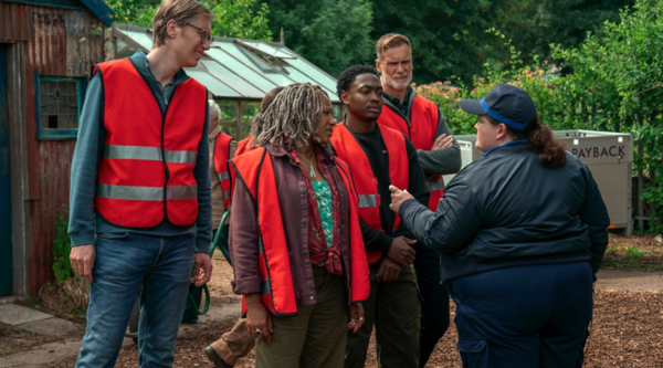 From left to right, Stephen Merchant, Clare Perkins, Gamba Cole, Darren Boyd and Jessica Gunning stand outdoors. Gunning is facing the rest of them, who look apprehensive.