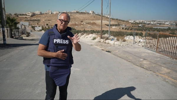 Matt Frei stands to camera wearing a bulletproof vest presenting Channel 4 News from Israel from 