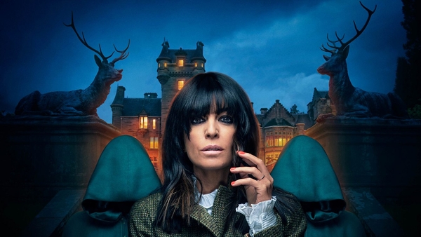 Claudia Winkleman is flanked by two hooded figures against a night-time backdrop of a Scottish castle
