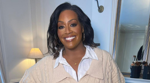 Alison Hammond looks into the camera, smiling, indoors