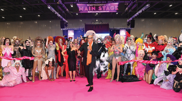 RuPaul stands in front of a group of drag queens at DragCon UK