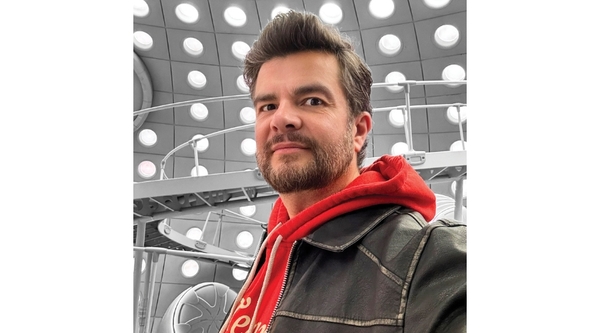 A selfie of a white man with grey-brown hair, wearing a red hoodie underneath a black leather jacket, as he stands in the newly revamped Doctor Who TARDIS