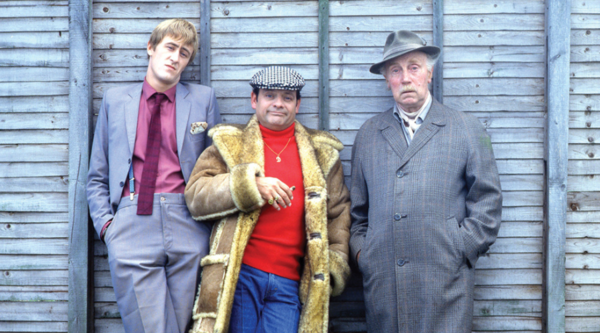 Rodney, Del Boy and Grandad from Only Fools and Horses stand in front of a fence and look into the camera