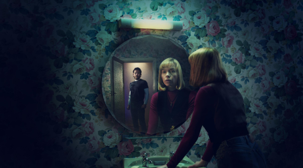 Shaun Evans and Anna Maxwell Martin stand in a dark room, Martin with her hands on the sink and looking at the mirror above it, with Evans looking at her in the mirror from the back of the room