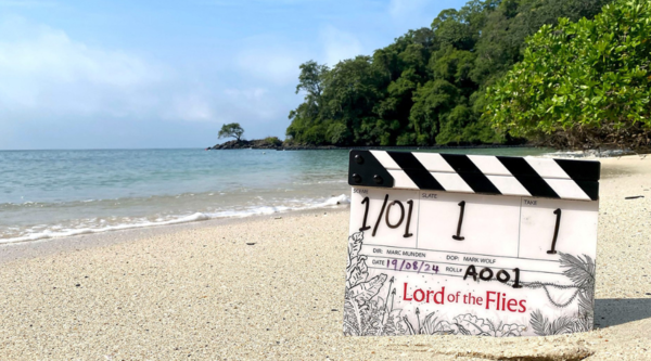 A clapperboard for Lord of the Flies, stood upright in the sand on a tropical beach