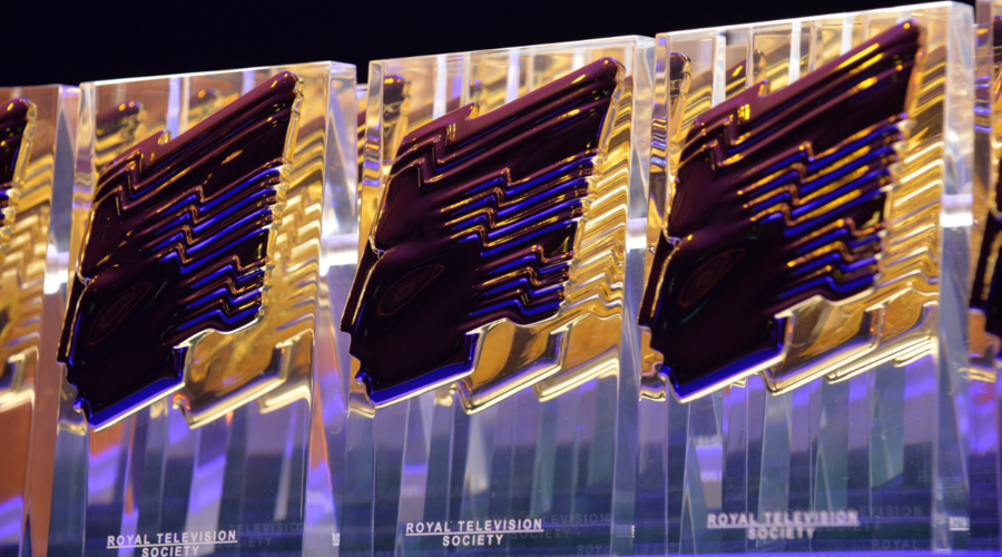 Three RTS Awards in a row, which are transparent rectangular awards with an RTS gold head attached