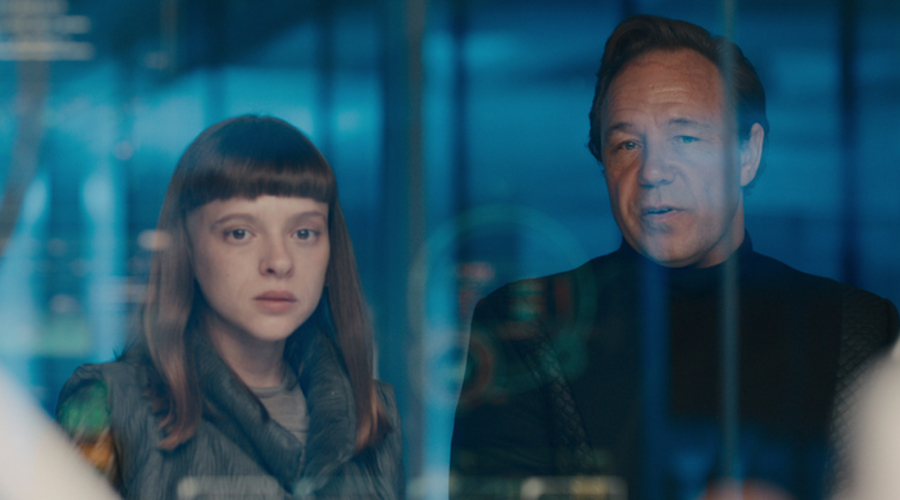 A woman, Shira Haas as Iris Maplewood, and a man, Stephen Graham as Elias Mannix, stand side by side in a blue room, in a still from Netflix series Bodies
