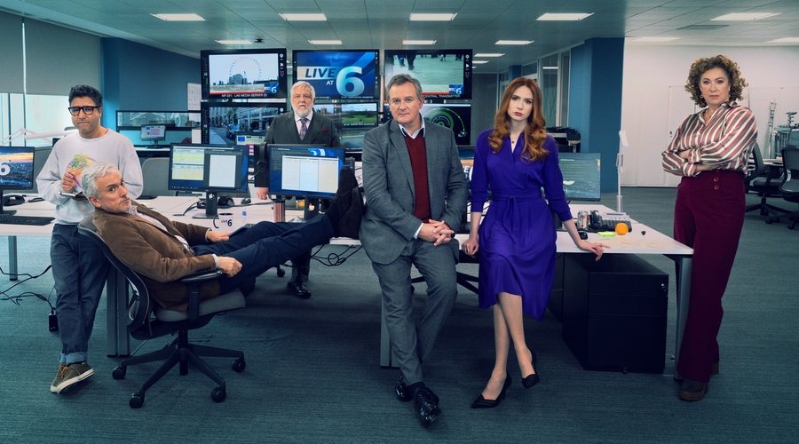 The cast of Douglas is Cancelled gather around the office of the fictional news programme Live at Six
