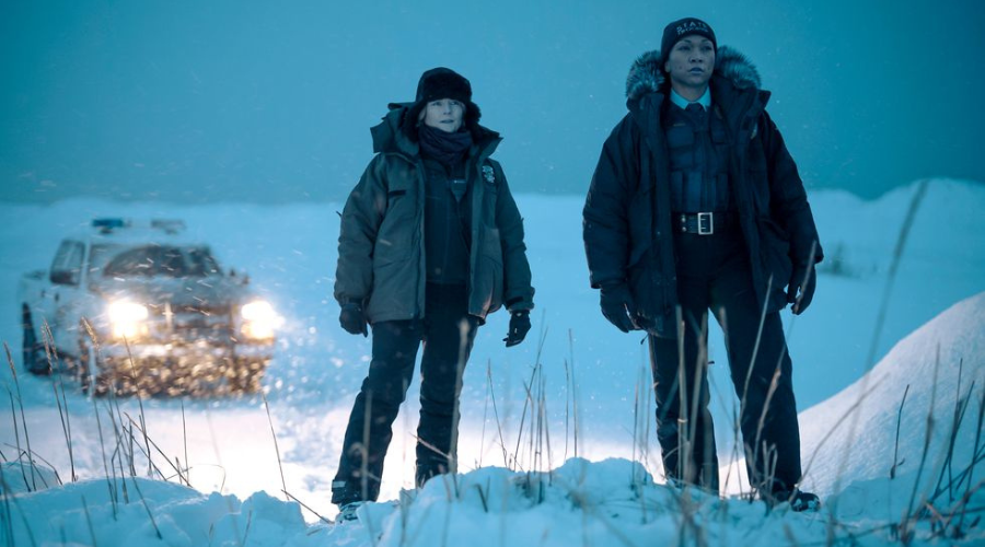 Jodie Foster and Kali Reis stand in a snowy, barren landscape in Alaska, dressed in wintery police uniform, playing detectives in True Detective: Night Country