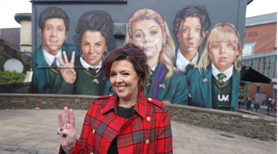 Lisa McGee stood in front of Derry Girls murial