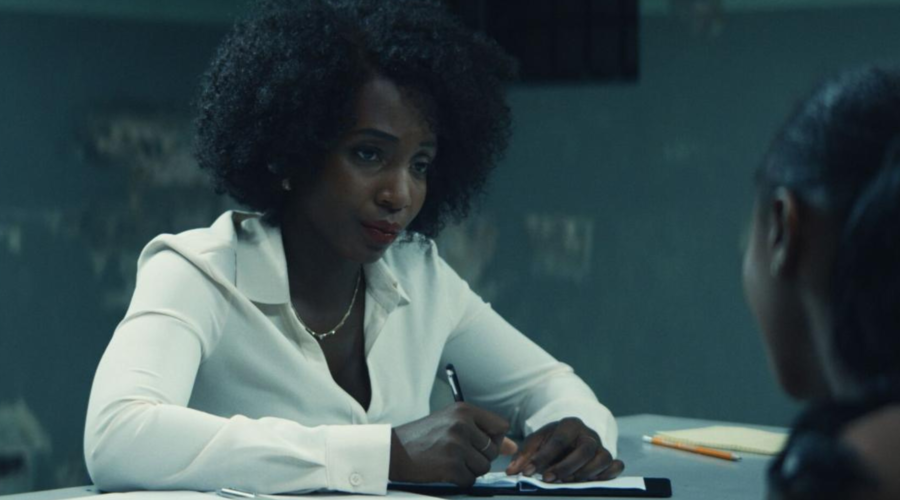 Tamara Lawrance sits in a police interrogation room, looking at a suspect, of whom all we see is the back of their head