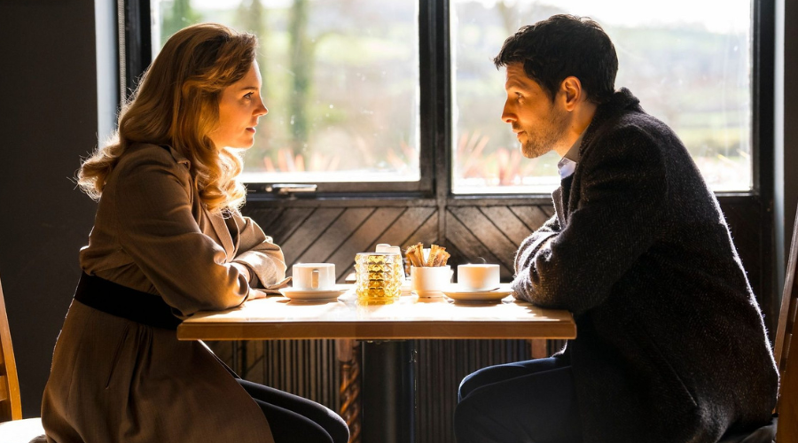 Annabel Scholey and Colin Morgan sit opposite each other at a table in a cafe