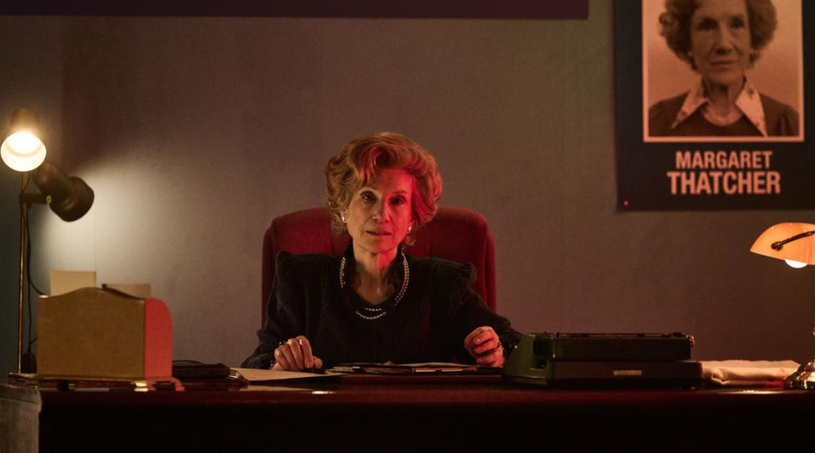 Harriet Walter, a white woman in her 70s, sits at a desk, with a campaign poster reading "MARGARET THATCHER" on the wall behind her and red light shining on half her face