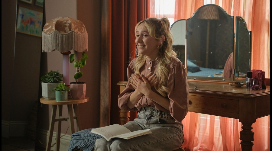 Rose Ayling-Ellis signs, sat in what appears to be her bedroom, crossing her hands over her chest while smiling