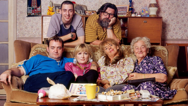 The cast of The Royle Family sit on and around the sofa in their living room