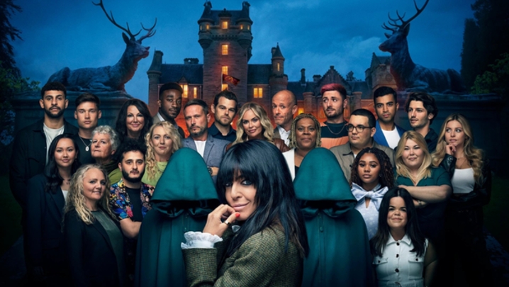 Claudia Winkleman looks at the camera, with series one contestants stood behind her