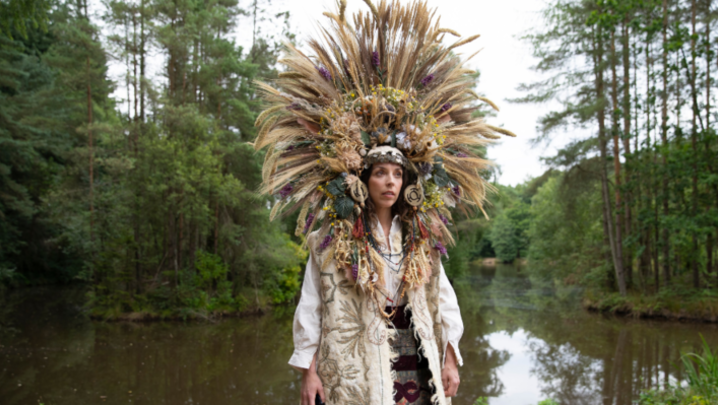 Bridget Christie as Linda stood in the forest with an elaborate headdress 