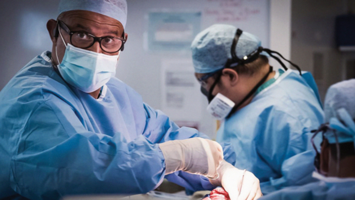 Two surgeons in the middle of operating, one in focus and the other out of focus