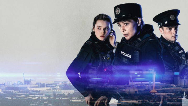 Three police officers stand in front of a grey background. Superimposed below them is a cityscape, with blue flares of light