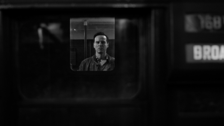 Andrew Scott, in character as Tom Ripley, looks out from a train window, looking menacing, in black and white