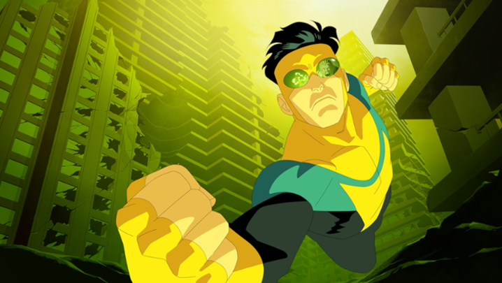The superhero Invincible looks into the camera, ready to throw punches, with a villain reflected in his goggles