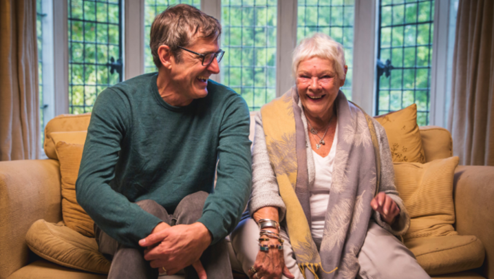 Louis Theroux and Dame Judi Dench laughing on a sofa